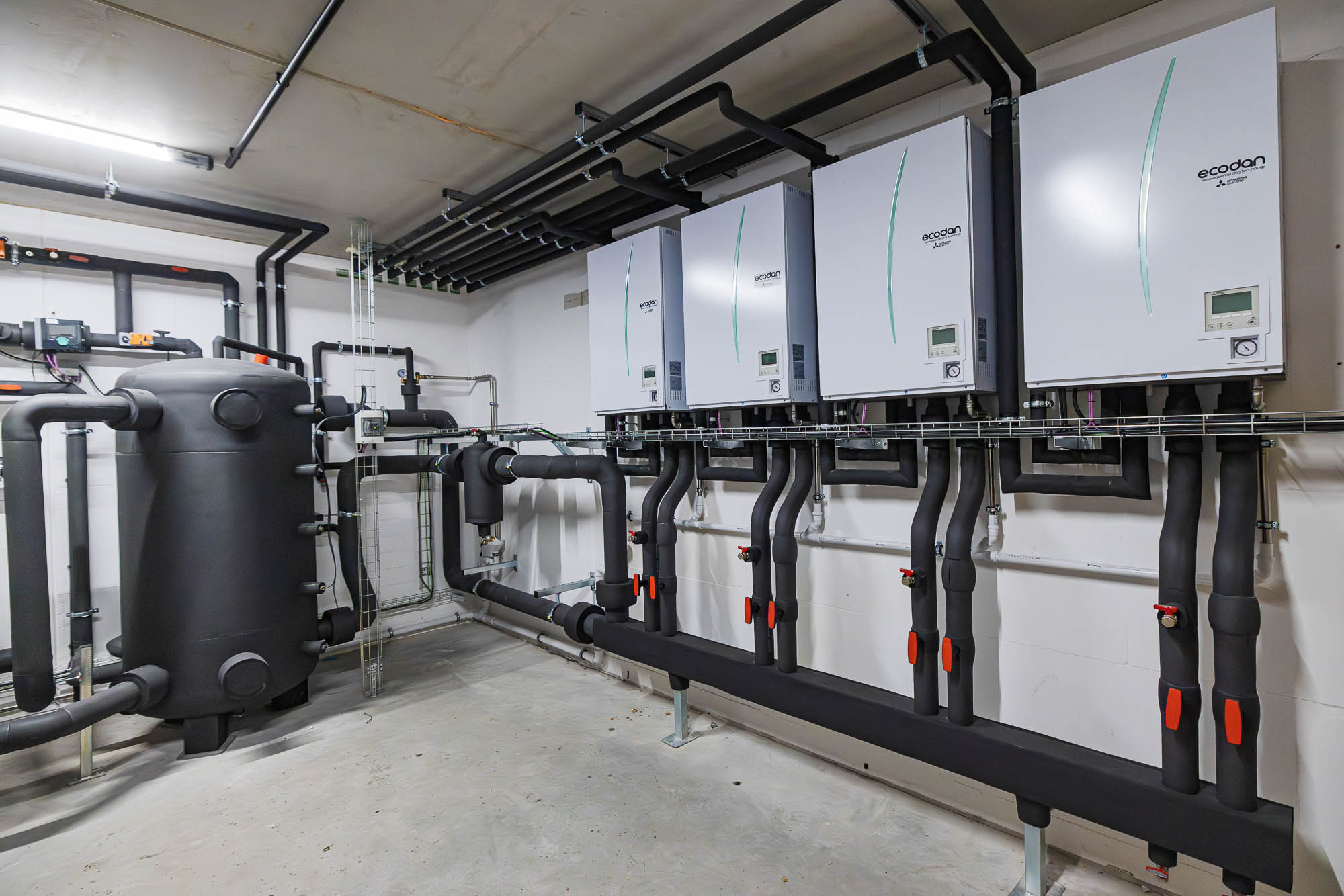 Technikzentrale mit wandhängenden Anlagenmodulen, Pufferspeicher und gedämmten Leitungen